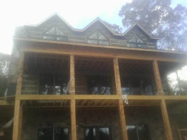 Dormers and porch framing on a large log home under construction — Roof Coating work by our crew in Cedar Grove