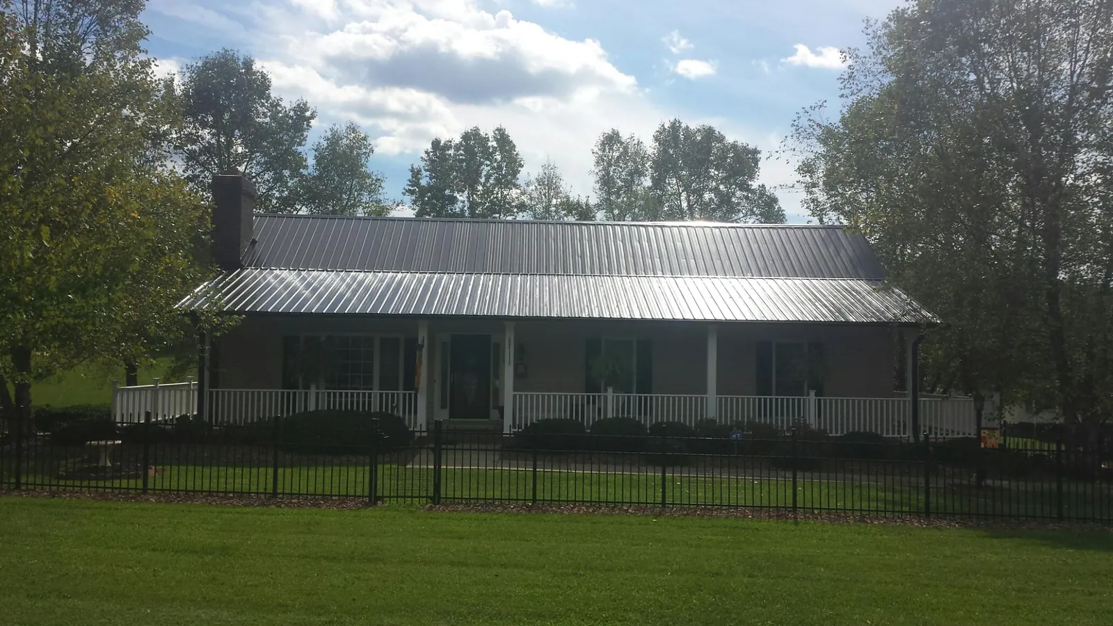 Gray metal roof on a brick ranch with a full width front porch — Gutter Guard Installation work by our crew in Cedar Grove